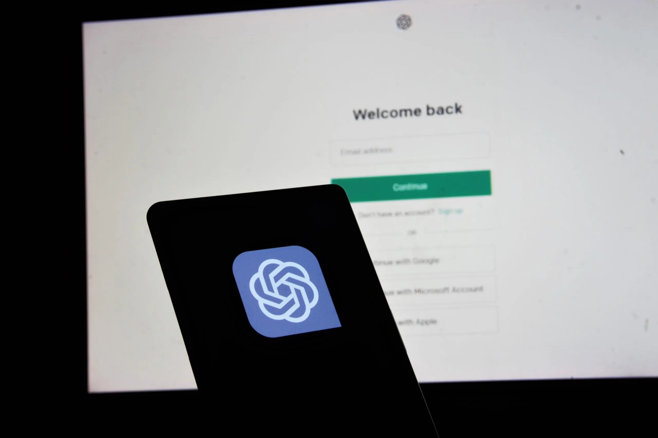 Smartphone affichant le logo de ChatGPT devant un écran de connexion